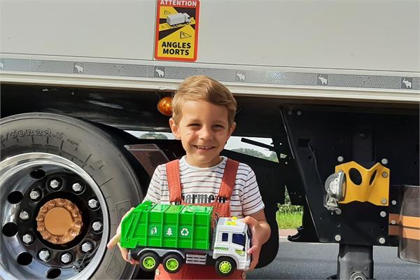 A child in front of a truck holding a toy truck