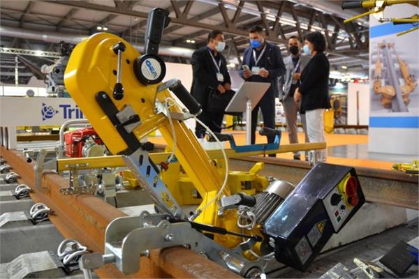 Un robot giallo che posiziona binari del treno in un padiglione espositivo