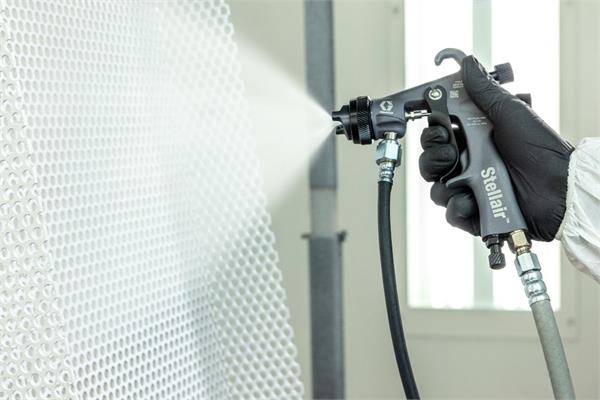 Application of white liquid paint on a metal mesh with Graco Stellair air spray gun
